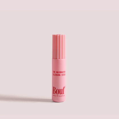 The Hairmaster Slicking Stick by Bouf, standing upright on a plain light pink background.