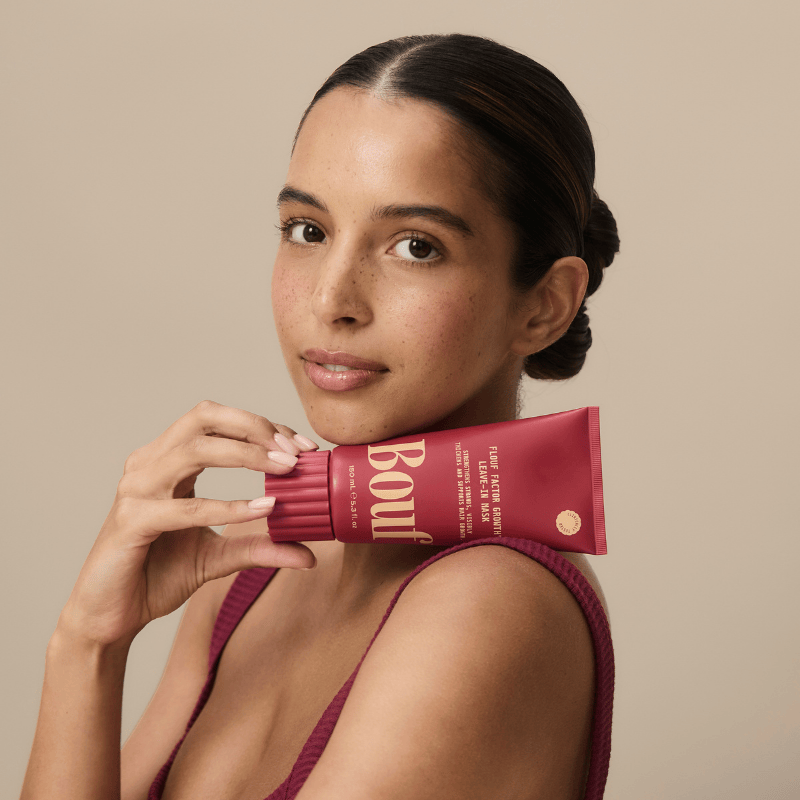 Woman holding a red product packaging against a beige background